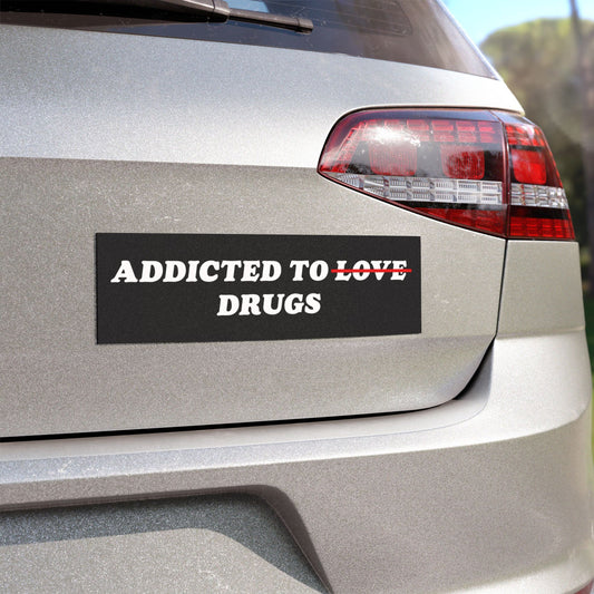 Silver hatchback rear displaying the Addicted To Love / Drugs Sticker & Magnet below the right taillight, illustrating a bold statement on mental health and therapy with a relatable, humorous twist.