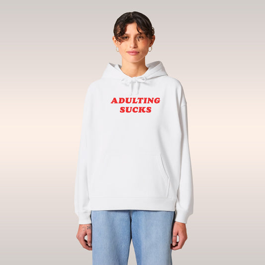 Adulting Sucks Hoodie worn by a person in glasses, featuring bold red text on a light pink comfy midweight hoodie.