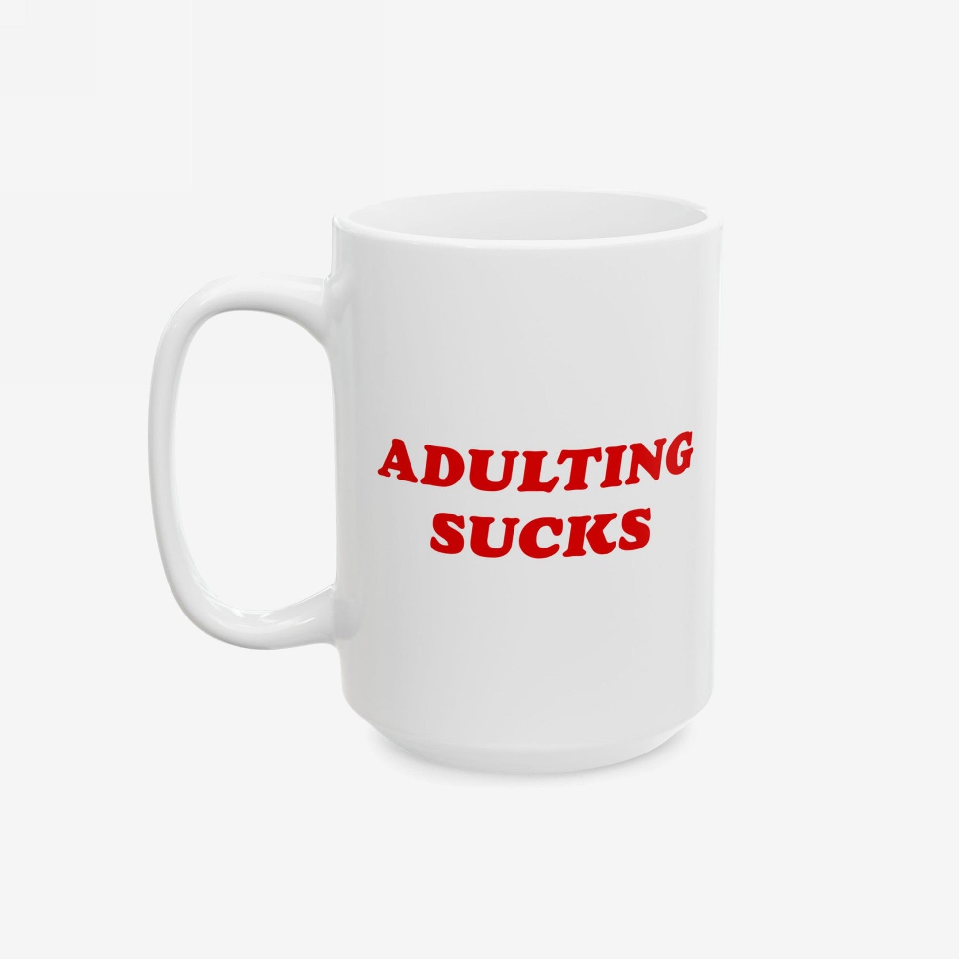 White ceramic mug featuring bold red text ADULTING SUCKS. Designed for those overwhelmed by daily life, this mug is both a statement and a practical, dishwasher-safe accessory for coffee enthusiasts.
