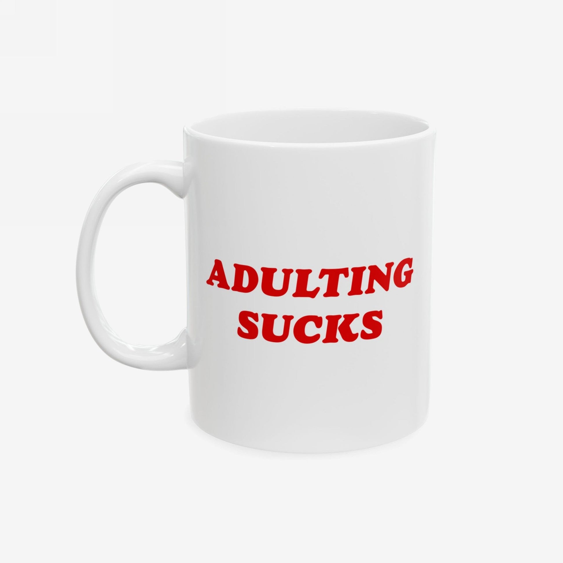 White ceramic mug with bold red text ADULTING SUCKS, epitomizing daily struggles. Ideal for office rebels and remote workers. Available in two sizes, dishwasher-safe, supporting mental health advocacy.