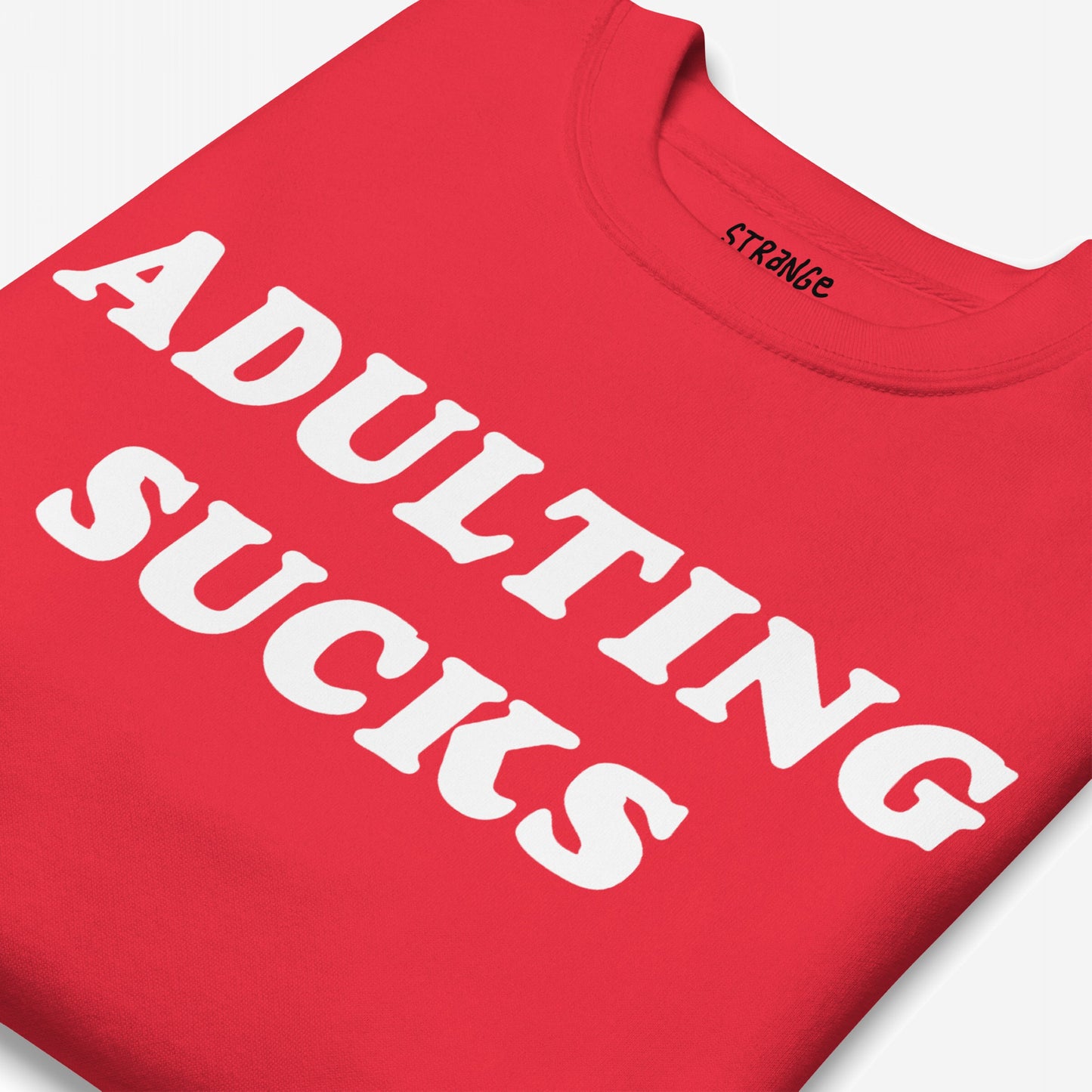 Adulting Sucks Sweatshirt EU: A folded red crew-neck sweatshirt with “ADULTING SUCKS” in bold white letters, ideal for expressing stress and humor. Part of Egoproof's mental health-themed apparel.