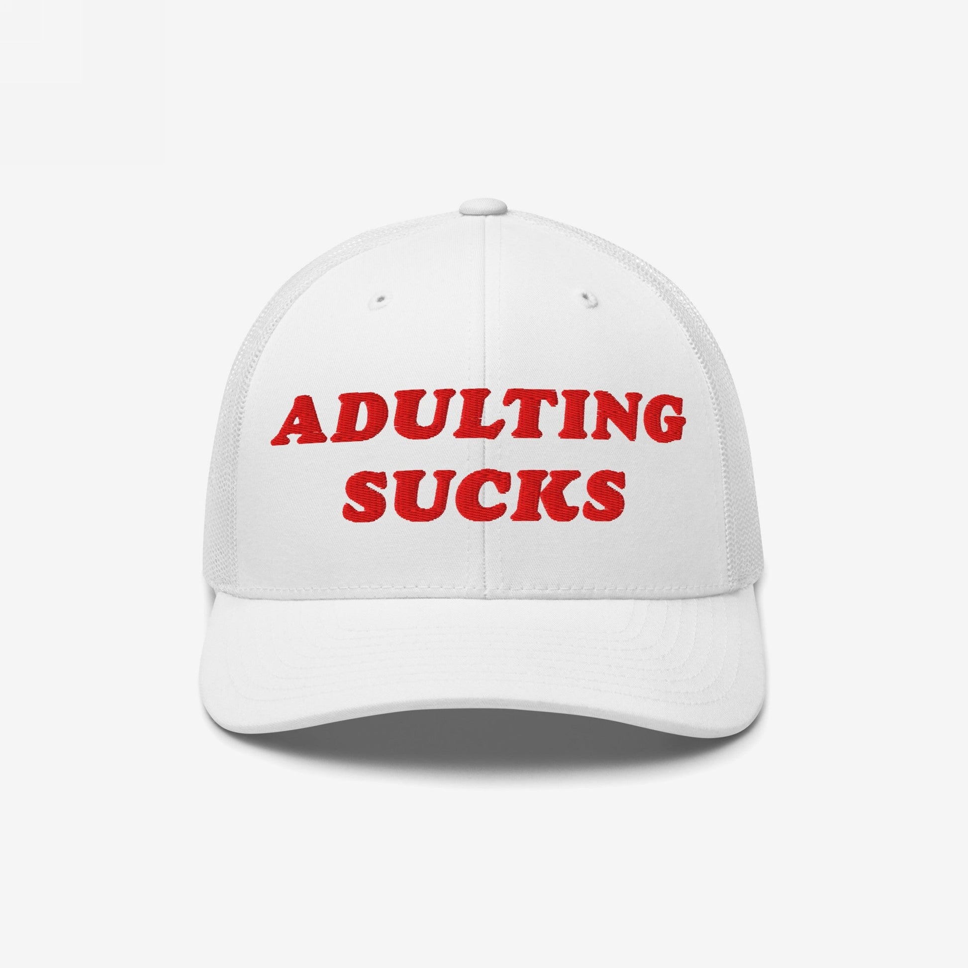 White mesh-back trucker cap with ADULTING SUCKS embroidered in bold red on front. Designed for those overwhelmed by life's demands, reflecting Egoproof's mission of relatable, powerful statements in everyday apparel.