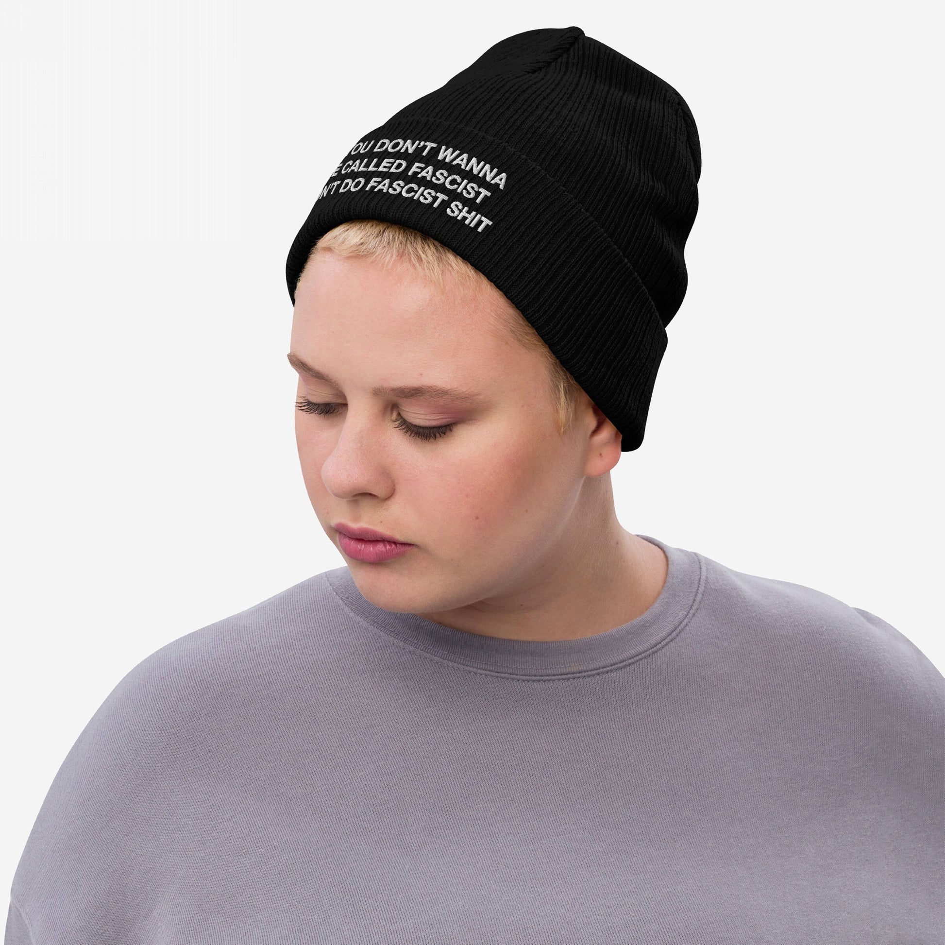 Anti-Fascist Beanie: A young person wears a ribbed black beanie with bold white text, promoting resistance. Ideal for making powerful statements against hate, embodying Egoproof's ethos of strength and defiance.