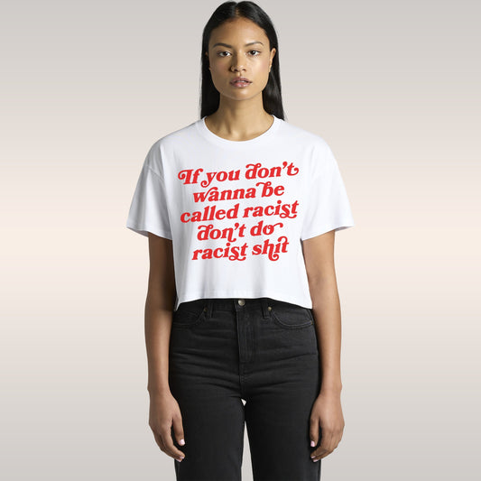 Young woman in car wearing the Anti-Racist Women's Baby Tee featuring bold message, paired with high-waisted jeans, hoop earr