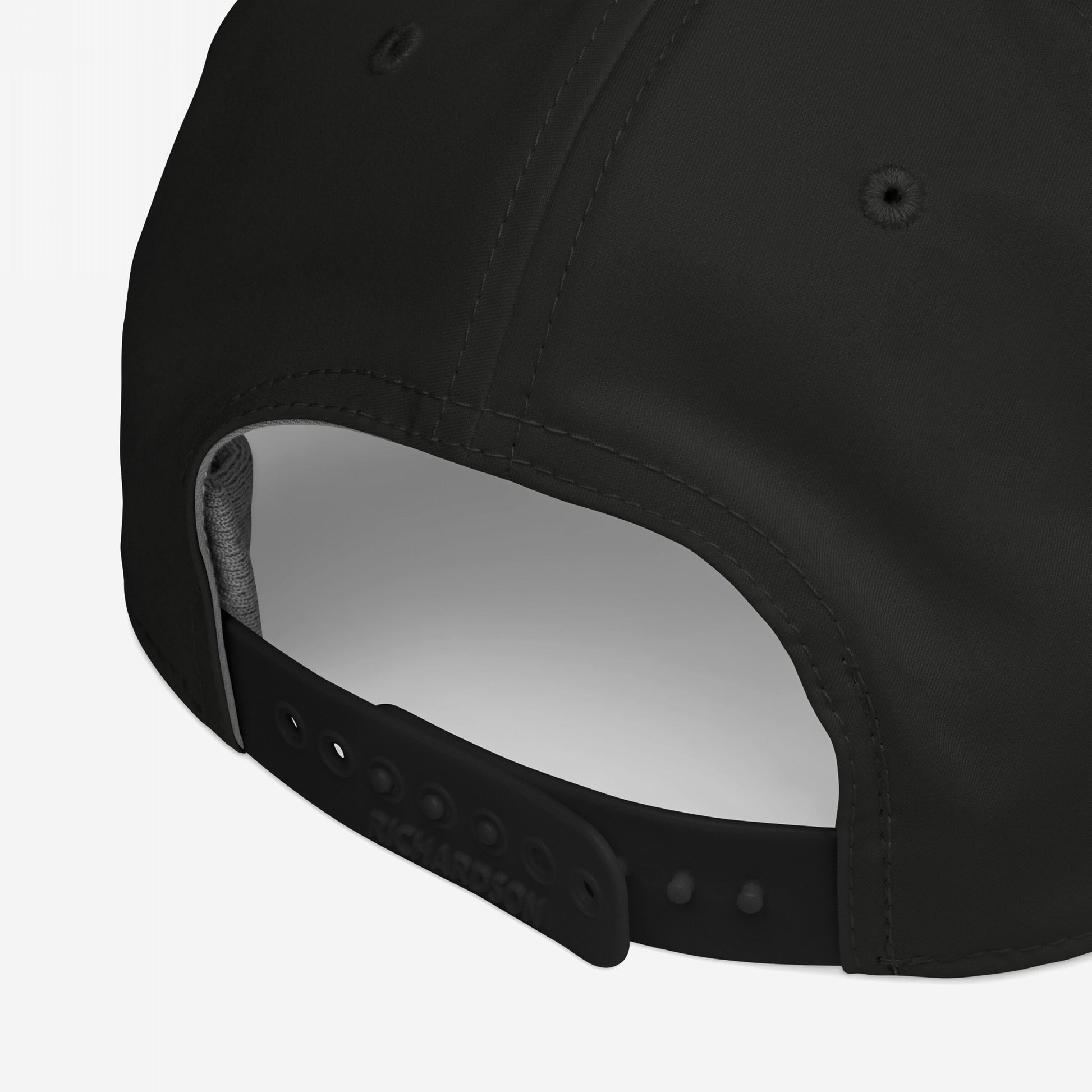 Anti-Racist Hat: Back view of a black snap-back baseball cap featuring an adjustable Richardson snap-strap, rear opening, stitching, and embroidered ventilation eyelet, embodying bold statements for impactful everyday wear.