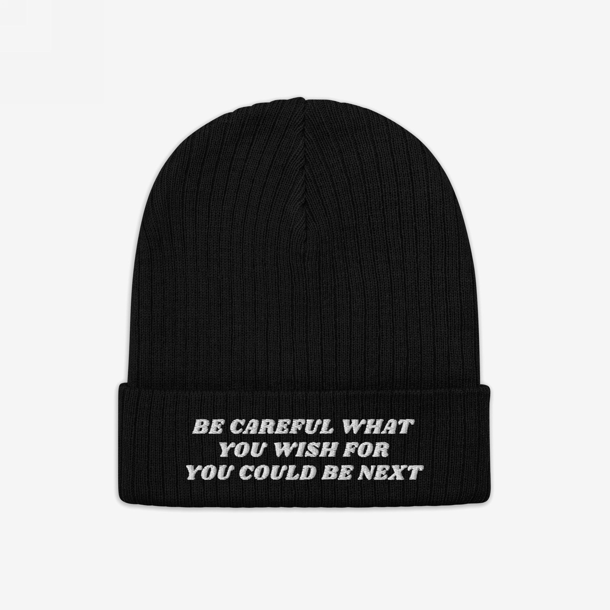 Black rib-knit beanie with folded-cuff, featuring white embroidered text BE CAREFUL WHAT YOU WISH FOR YOU COULD BE NEXT on front. The Be Careful Hat makes a bold, unapologetic style statement.
