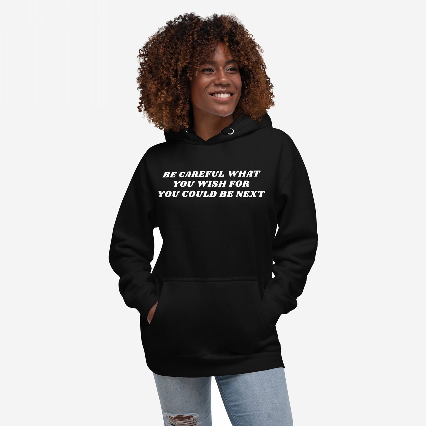 Young woman with curly hair wearing the Be Careful Hoodie EU, featuring bold white text warning against complacency. A midweight, unisex design for activists and disruptors, supporting ACLU.