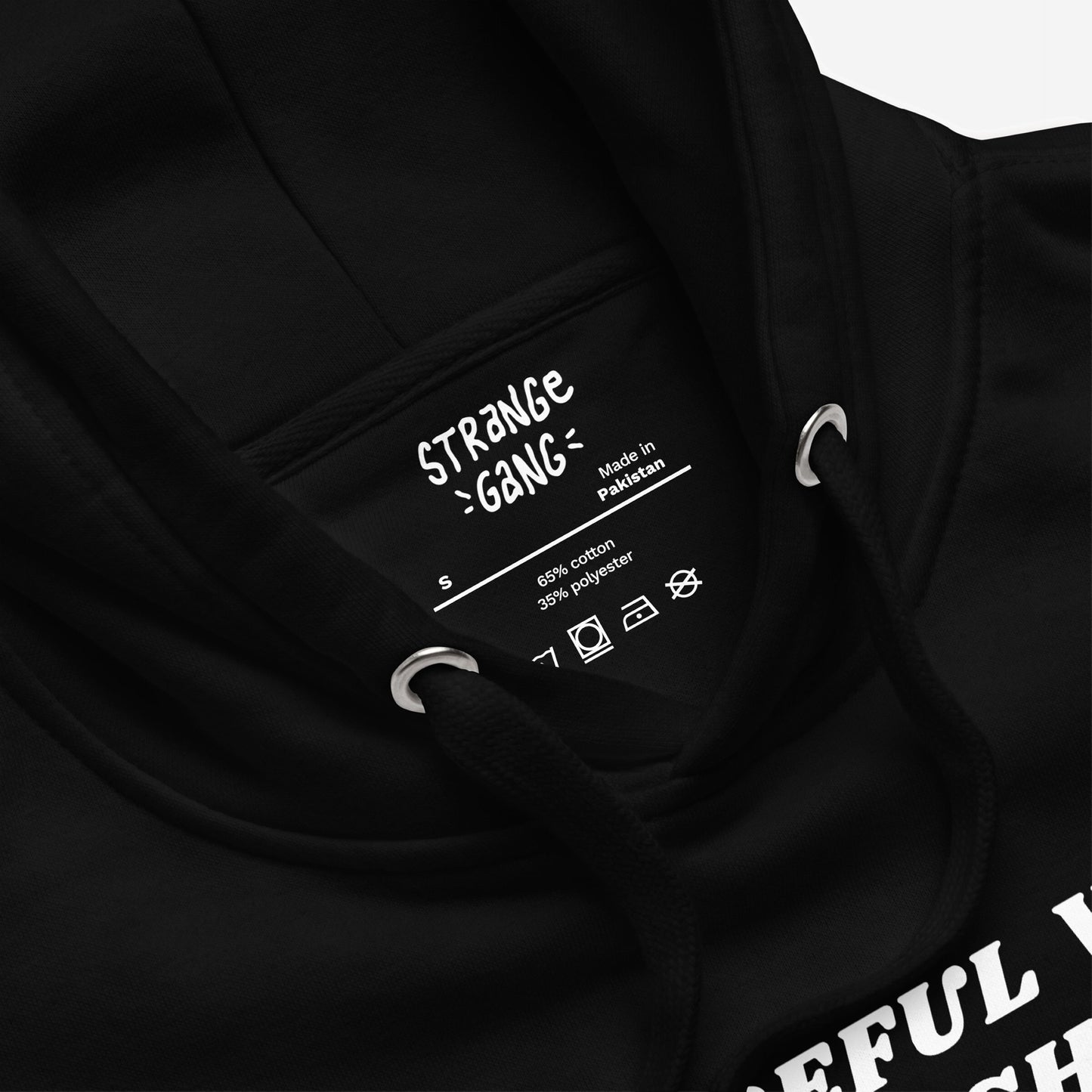 Be Careful Hoodie EU close-up shows neck details: brand name, Made in Pakistan label, size S, fabric content, care symbols, black drawstring, metal eyelets; embodies bold activism.