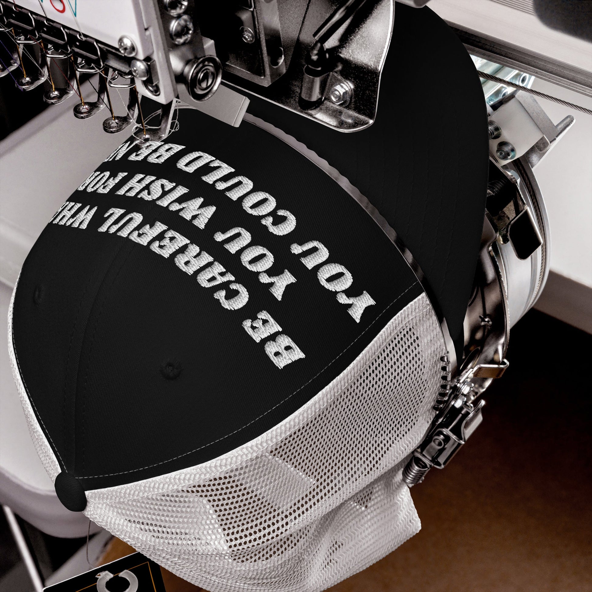 Automated embroidery head stitching Be Careful Hat slogan onto a black-and-white mesh trucker cap, highlighting its bold, unapologetic messaging for anti-fascists and progressives.