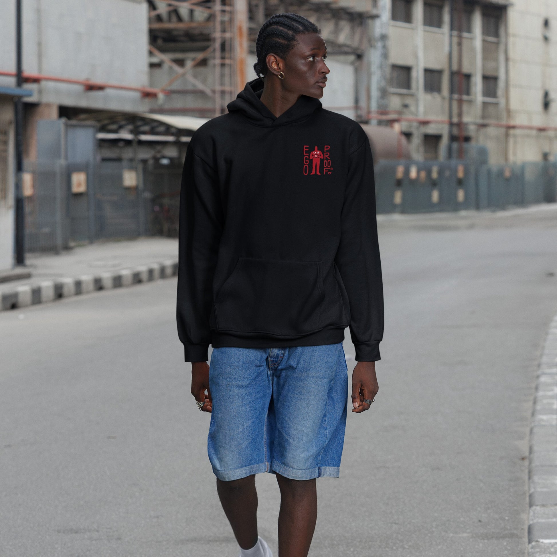Young person in a black Fucks To Give Hoodie with a red chest graphic, denim shorts, and white sneakers, embodying Egoproof's ethos of emotional minimalism and unapologetic self-expression.