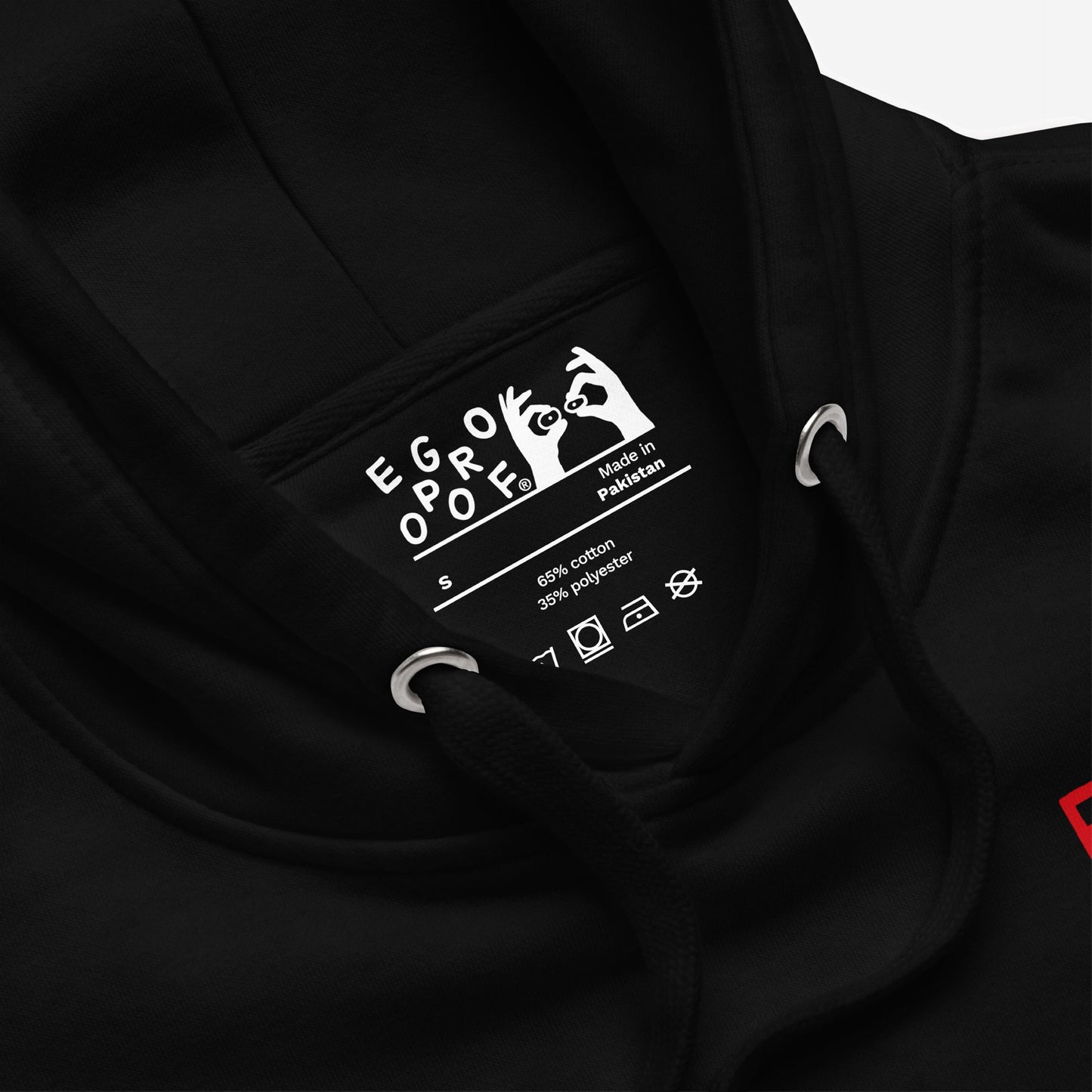 Close-up of Fucks To Give Hoodie EU's neck, showing label with EGO PROOF, size S, and fabric details. Includes care icons, drawcord, and metal eyelet. Cozy mental health statement wear.