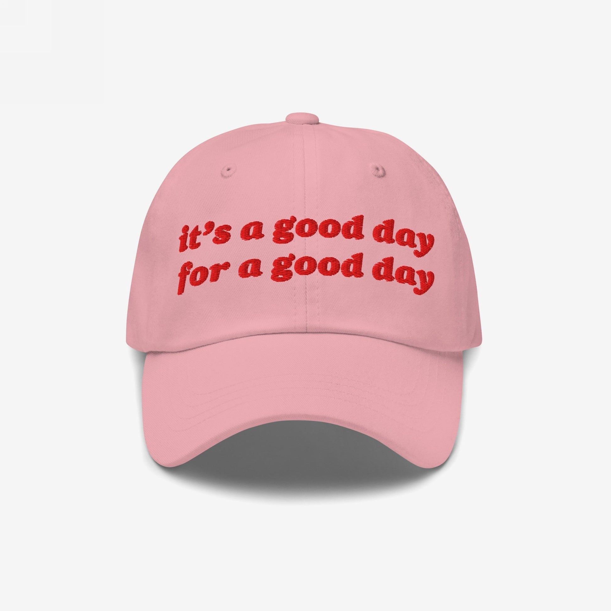 Good Day Hat features a light-pink dad hat with red embroidered text, it's a good day for a good day, promoting positivity and mental health awareness through stylish, empowering fashion.