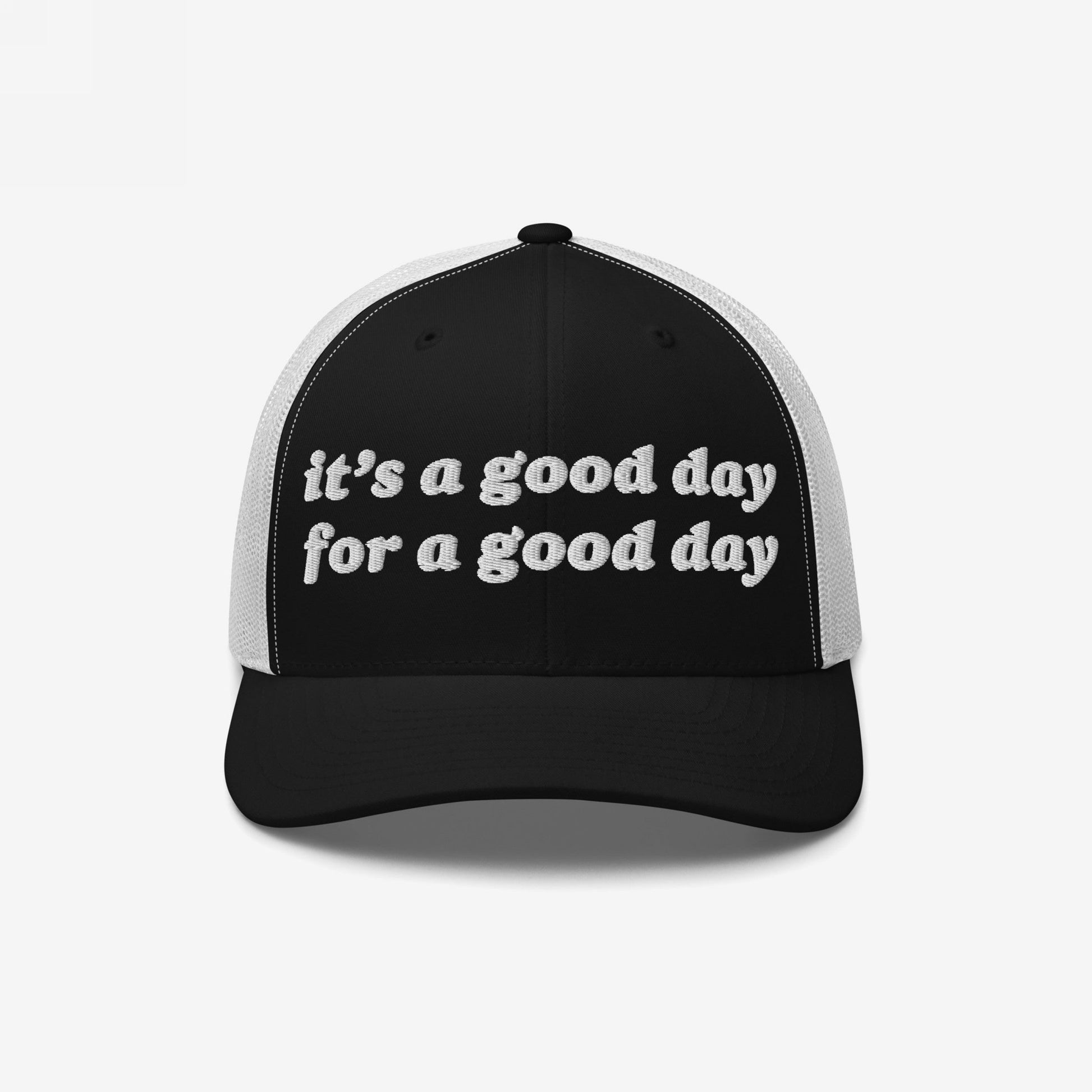 The Good Day Hat features a black-and-white mesh-back design with the phrase it’s a good day for a good day embroidered on the front, promoting positivity and mental health awareness.