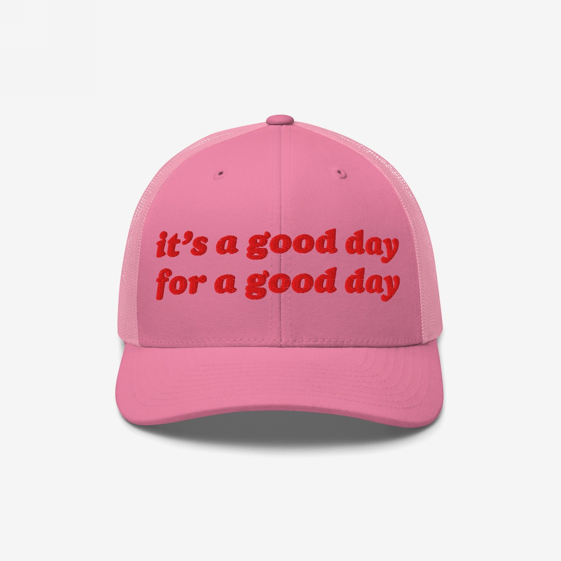 Pink trucker-style baseball cap featuring red embroidered text: “it’s a good day for a good day.” The Good Day Hat embodies positive vibes, ideal for mental health advocates.
