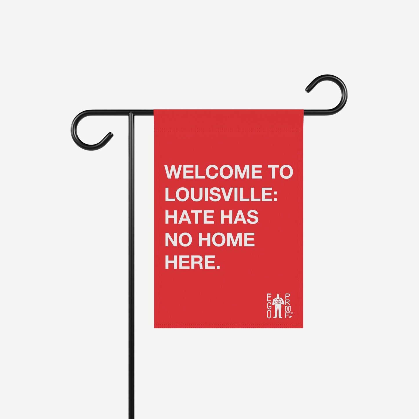 Custom Hate Has No Home Here Garden Flag displayed on a black metal stand. The red flag features bold white text promoting unity and acceptance, customizable with your community name, embodying Egoproof's empowering message.