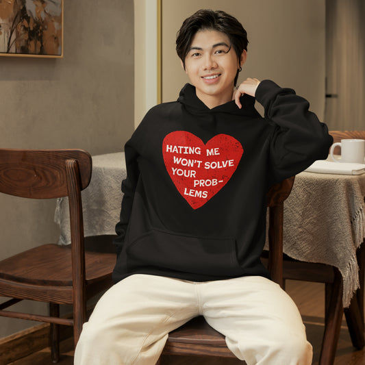 Young person sitting indoors wearing a black No Hate Hoodie with red heart and statement against hate on the front.