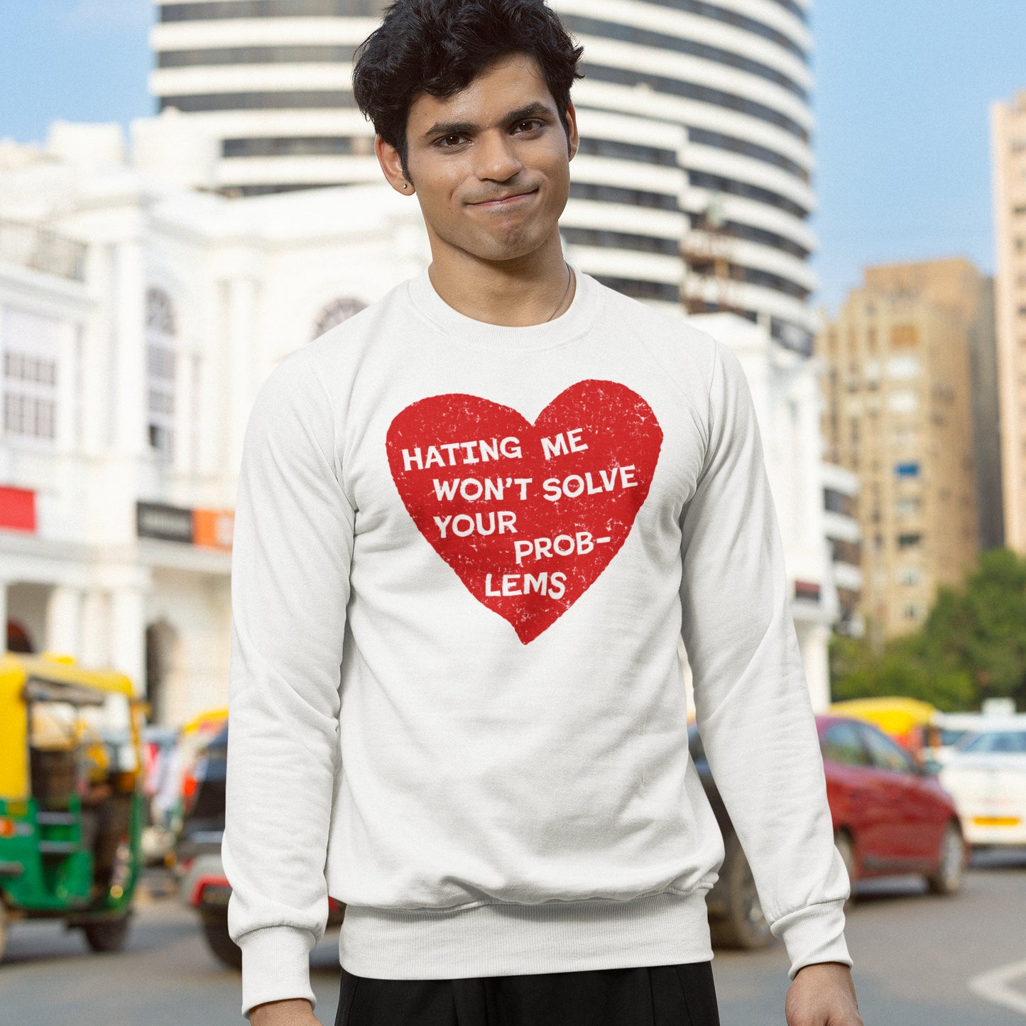 Young man wearing a white No Hate Hoodie & Sweatshirt with a bold red heart and empowering message in an urban setting.