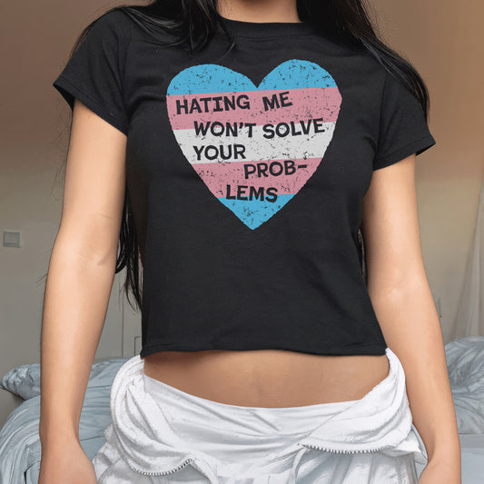 No Trans Hate Women's Baby Tee with trans pride heart design and bold message "Hating Me Won't Solve Your Problems" on black fitted crop top.