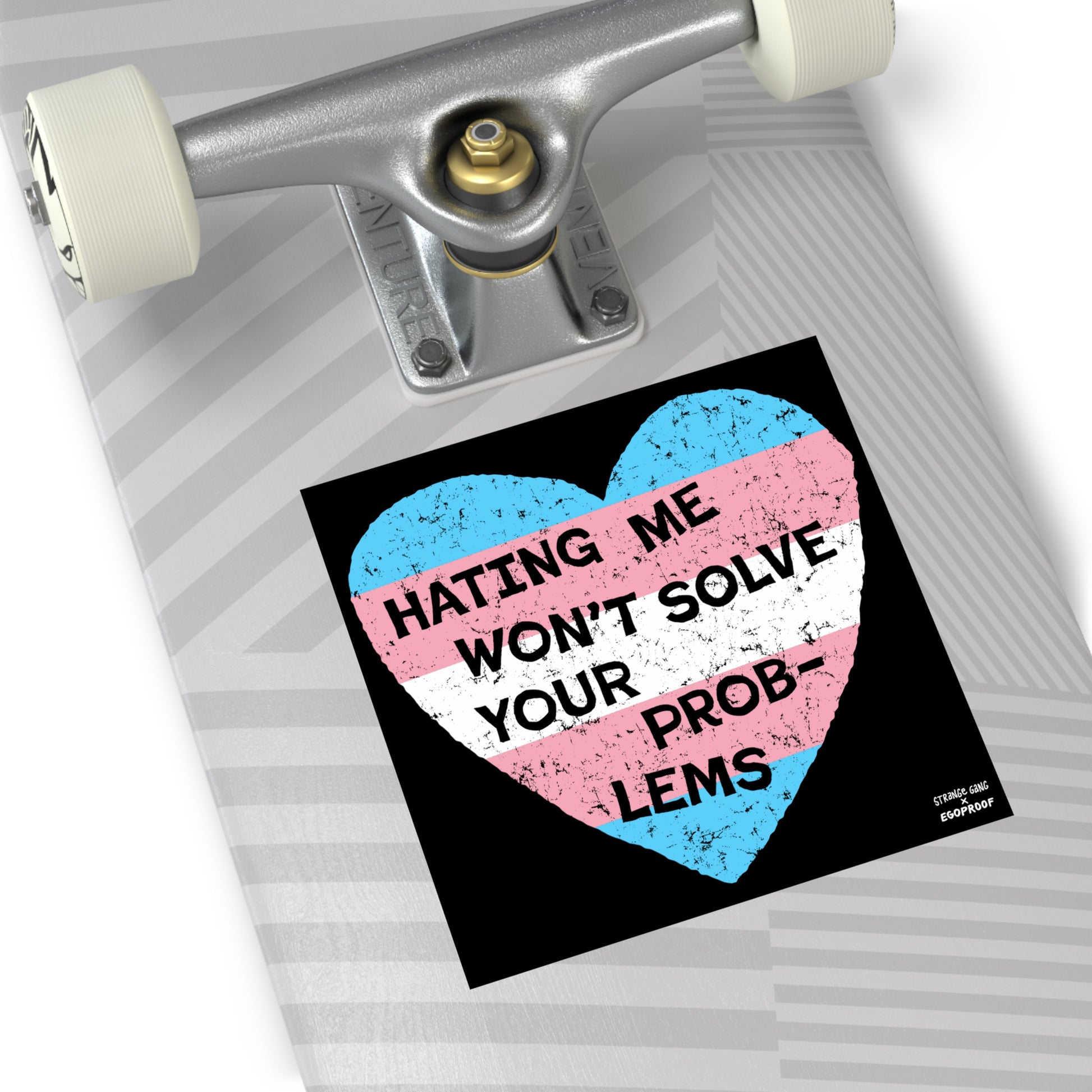 No Trans Hate Sticker & Magnet displaying trans flag heart with "Hating Me Won’t Solve Your Problems" on skateboard deck.