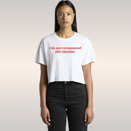 Woman wearing Timeline Women's Baby Tee black cropped shirt with white text sitting in car seat wearing sunglasses and hoop e