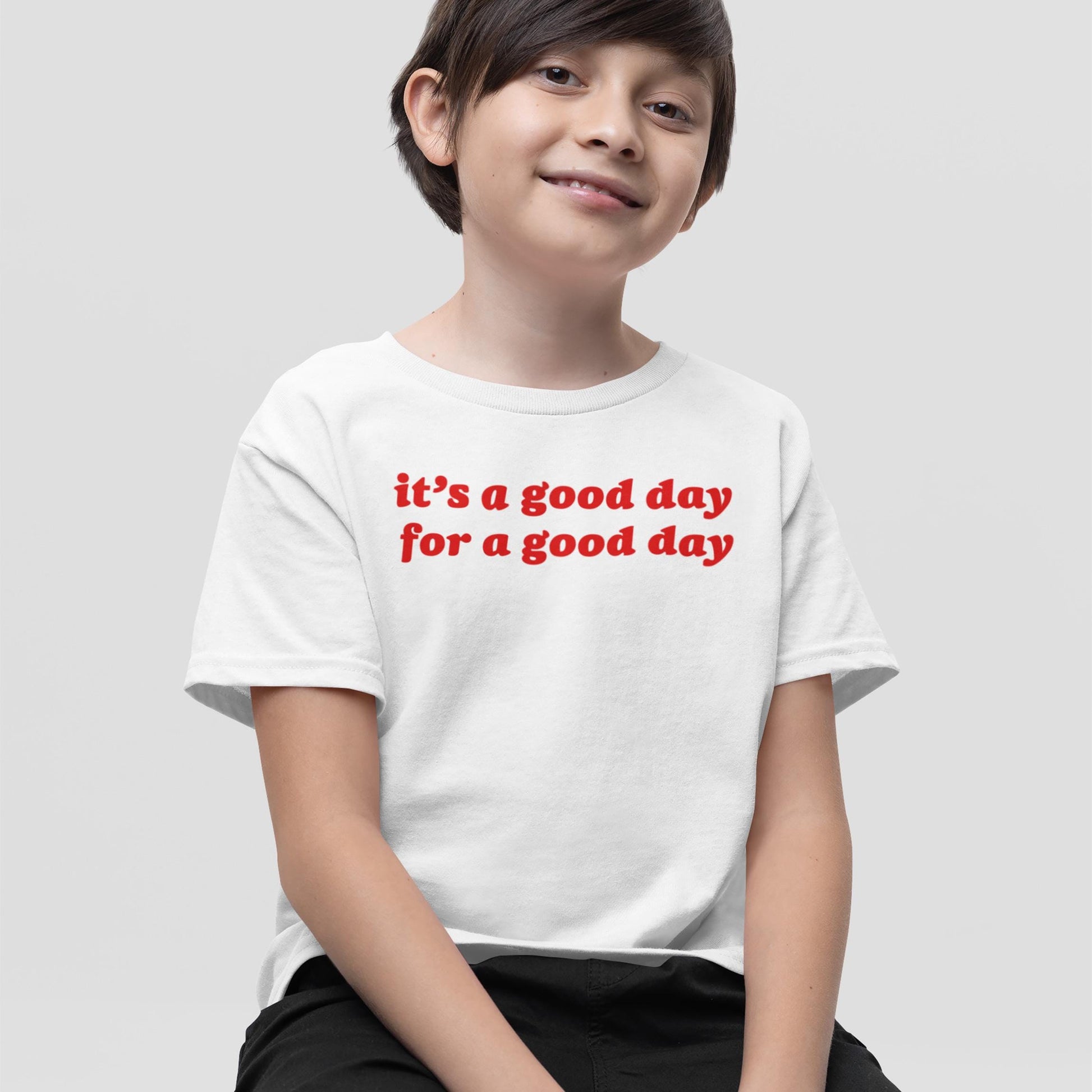 Child wearing the Good Day Kids T-shirt EU featuring the uplifting message “it’s a good day for a good day” in bold red letters, embodying playful confidence and optimism.