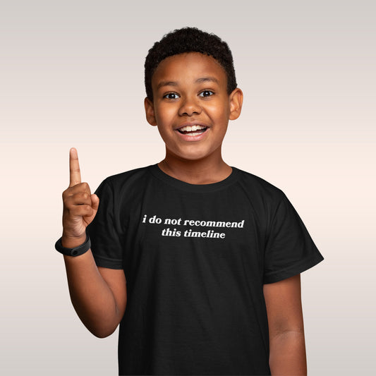 Young boy smiling, wearing the Timeline Kids T-shirt EU featuring the phrase “i do not recommend this timeline” in white