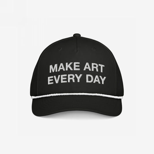 Make Art Every Day Hat featuring a black trucker-style design with white embroidery, braided rope detail above the brim, and adjustable back. A wearable mantra motivating creativity and resilience.