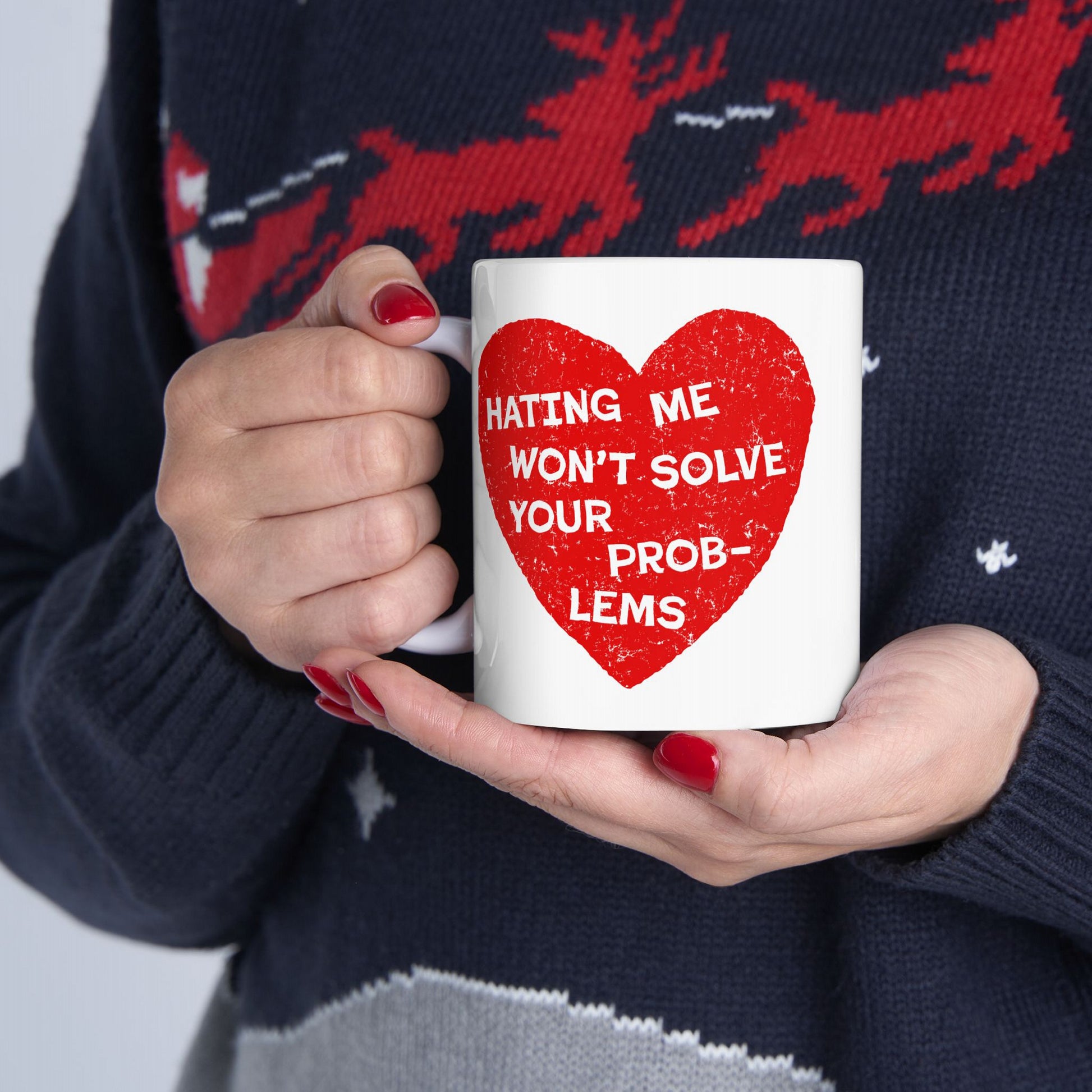 No Hate Mug featuring "Hating Me Won't Solve Your Problems" quote inside a red heart, held by a person wearing a navy sweater.