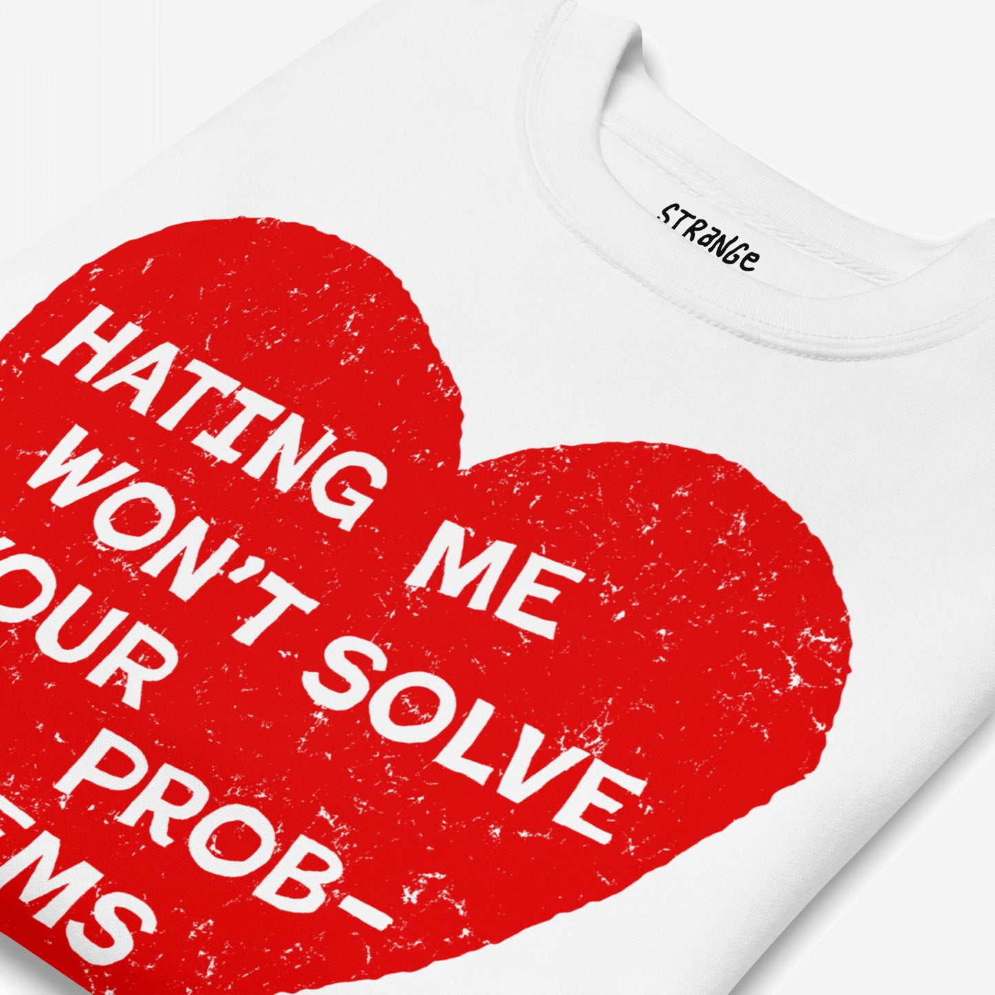 No Hate Sweatshirt EU features a folded white T-shirt with a distressed red heart and bold slogan: “HATING ME WON’T SOLVE YOUR PROBLEMS.” Label reads “STRÄNGE.”