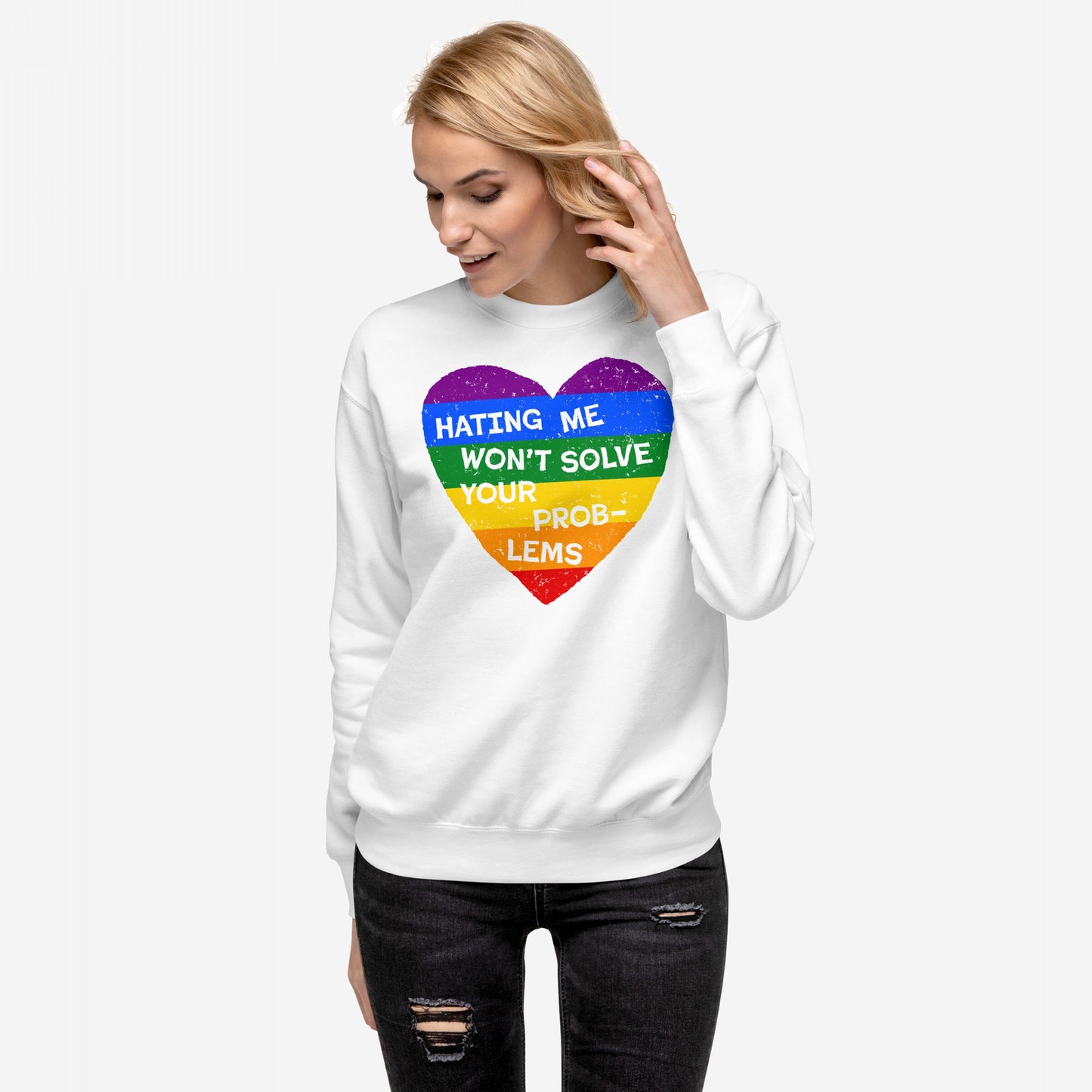 A blonde woman wears the No LGBTQ Hate Sweatshirt EU, featuring a distressed rainbow heart with the slogan HATING ME WON’T SOLVE YOUR PROBLEMS, paired with black ripped jeans.