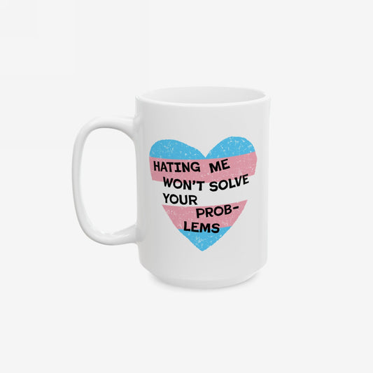 The No Trans Hate Mug features a pastel-striped heart with the phrase “Hating Me Won’t Solve Your Problems” printed on both sides, embodying trans pride and empowerment.