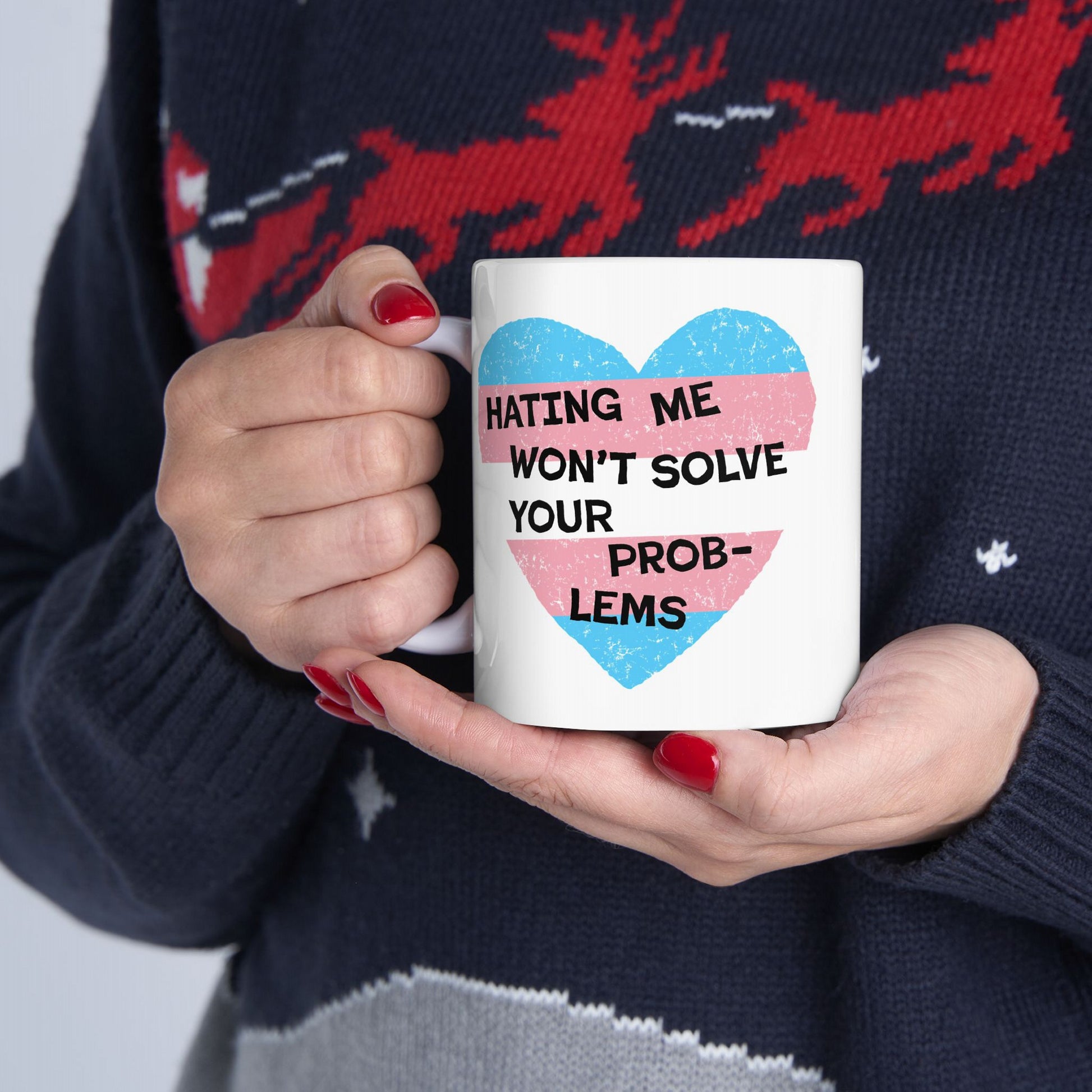 Person holding the No Trans Hate Mug with a pastel-striped heart and bold quote. The ceramic mug, designed with Strange Gang, symbolizes trans pride, empowerment, and supports The Trevor Project.