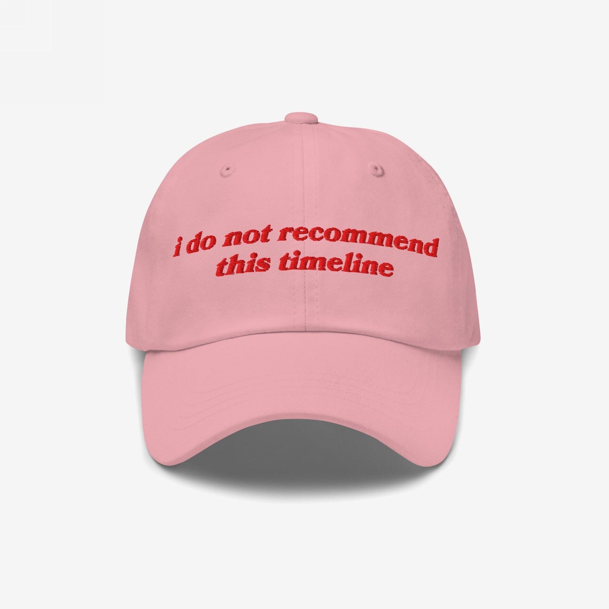 Light-pink dad hat with red embroidery reads “i do not recommend this timeline.” A playful yet poignant statement piece for navigating modern chaos, aligning with Egoproof’s mission of impactful, mental health-conscious apparel.