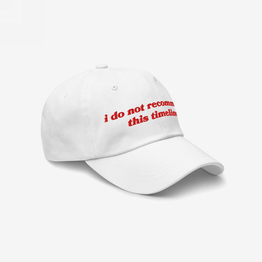 White six-panel baseball cap with i do not recommend this timeline in red embroidery. A nod to modern irony and resilience, reflecting Egoproof's ethos of powerful statements for mental health awareness.