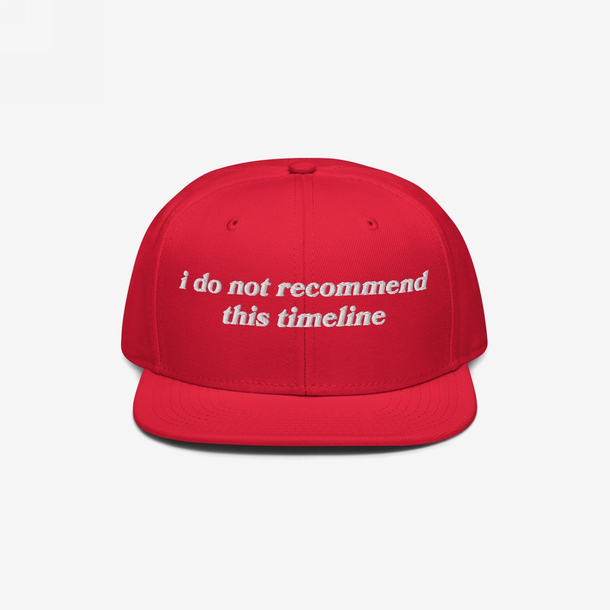 Red snapback cap with flat brim featuring white embroidered text reading “i do not recommend this timeline.” Ideal for irony enthusiasts, this Timeline Hat is styled for modern chaos and mental health awareness.