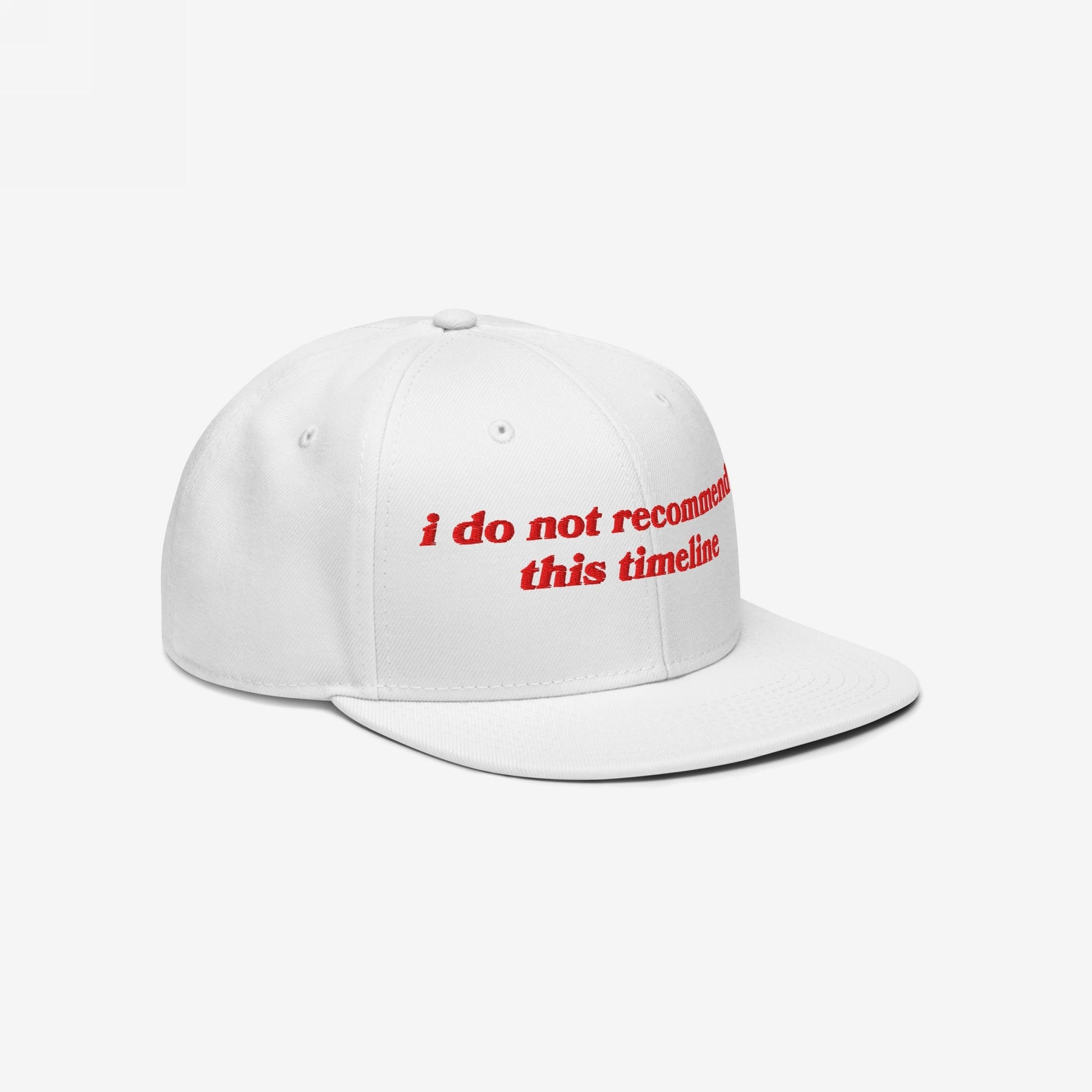 White flat-brim snapback hat with red embroidered text reading i do not recommend this timeline. The Timeline Hat embodies sarcasm and resilience, ideal for those navigating modern chaos with humor.