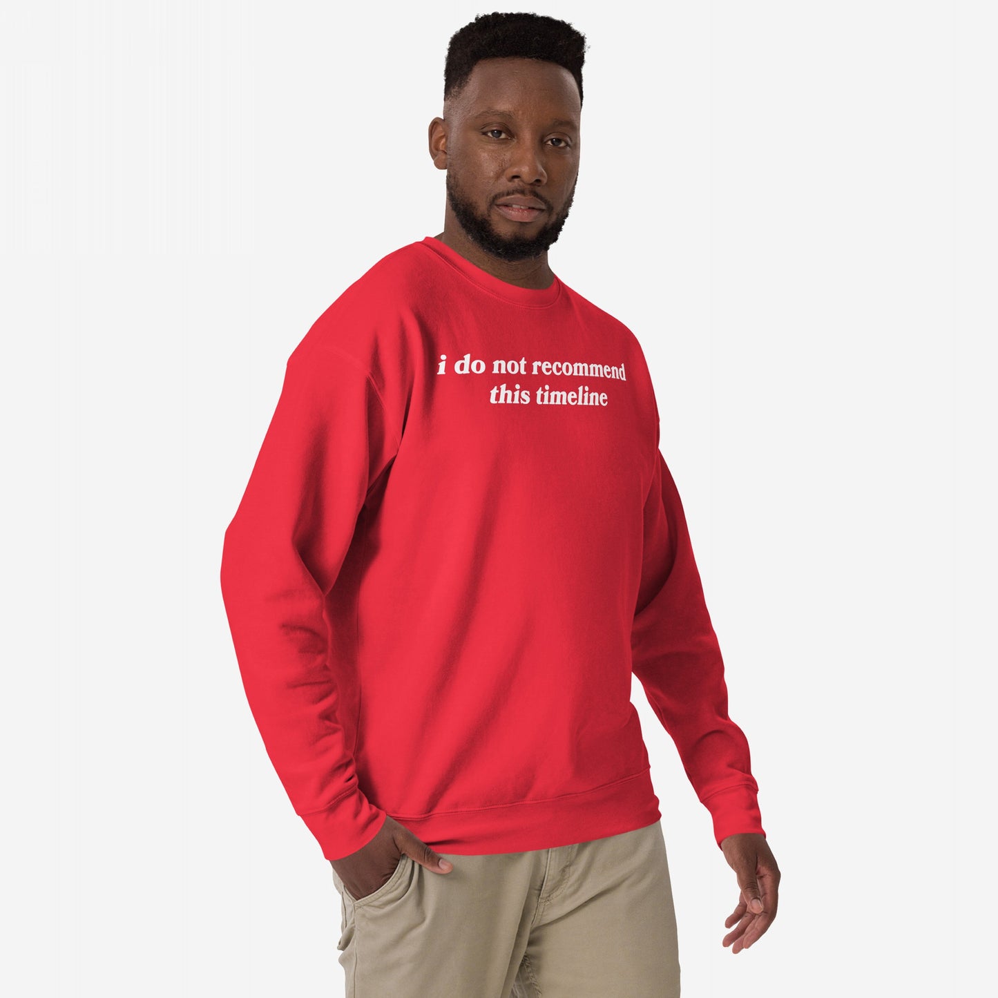 Black man models the Timeline Sweatshirt EU, featuring the statement i do not recommend this timeline. Paired with khaki pants, this midweight crewneck captures humor and burnout awareness.