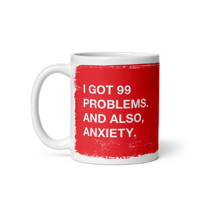 White ceramic 99 Problems Mug with red text stating "I got 99 problems. And also, anxiety." on both sides.
