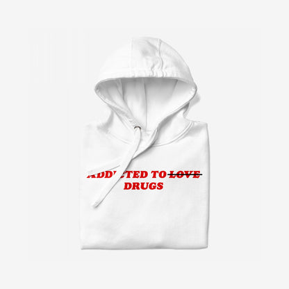 Folded white hoodie titled Addicted To Love / Drugs Hoodie EU features bold red text, ADDICTED TO LOVE, with TO LOVE crossed out and DRUGS beneath. Ideal for self-care or gifting.