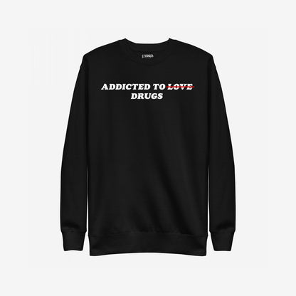 Black crewneck sweatshirt featuring bold white text ADDICTED TO LOVE with LOVE crossed out in red, replaced by DRUGS. The Addicted To Love / Drugs Sweatshirt EU symbolizes dark humor and candid self-expression.