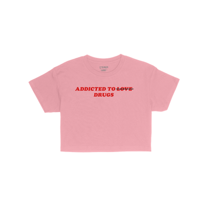 Addicted To Love / Drugs Women's Baby Tee in pink with bold text "Addicted to Drugs" and crossed out "Love" on front, fitted 