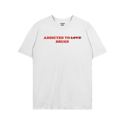 White unisex tee with bold red text "Addicted To Love" crossed out and replaced with "Drugs," titled Addicted To Love / Drugs