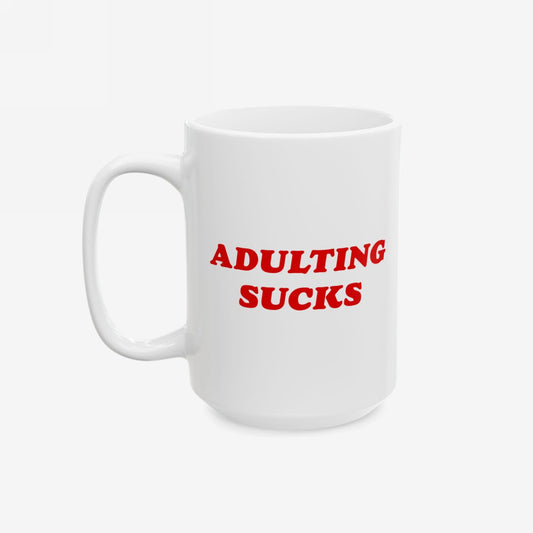 White ceramic mug featuring bold red text ADULTING SUCKS. Designed for those overwhelmed by daily life, this mug is both a statement and a practical, dishwasher-safe accessory for coffee enthusiasts.