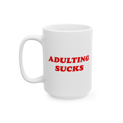 White ceramic mug featuring bold red text ADULTING SUCKS. Designed for those overwhelmed by daily life, this mug is both a st