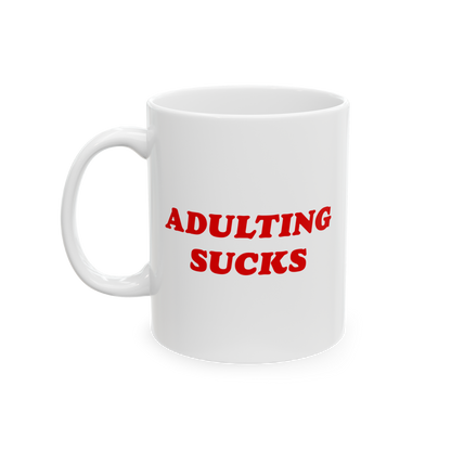 White ceramic mug with bold red text ADULTING SUCKS, epitomizing daily struggles. Ideal for office rebels and remote workers.