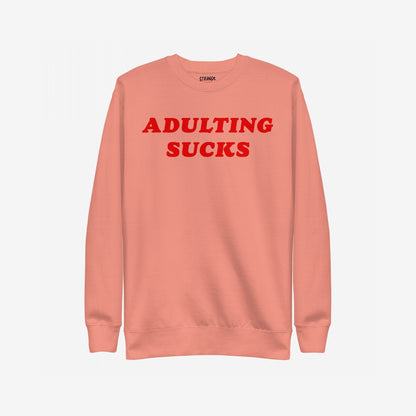 Adulting Sucks Sweatshirt EU featuring bold red text ADULTING SUCKS on a salmon-coral crewneck, ideal for expressing burnout and humor, reflecting Egoproof's mental health-focused apparel ethos.