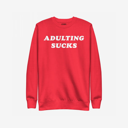Adulting Sucks Sweatshirt EU: A red crewneck sweatshirt featuring bold white “ADULTING SUCKS” text, perfect for expressing the struggles of everyday life with humor and style.