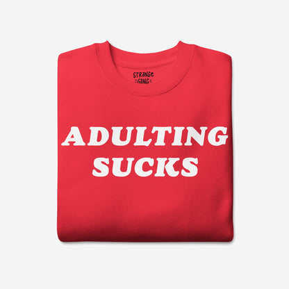 Adulting Sucks Sweatshirt EU: A folded red crewneck with bold white ADULTING SUCKS text on the front, perfect for expressing the stress and humor of modern adult life.