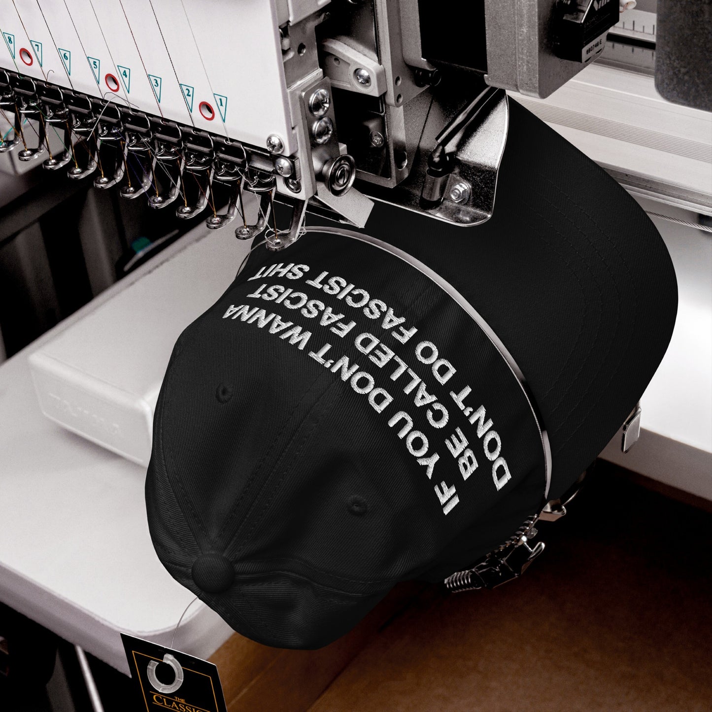 Anti-Fascist Hat in an embroidery machine, stitching the bold slogan “IF YOU DON’T WANNA BE CALLED FASCIST DON’T DO FASCIST SHIT,” embodying Egoproof’s commitment to making powerful statements through wearable art.