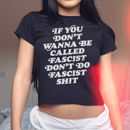Anti-Fascist Women's Baby Tee featuring bold white text on a black, short-sleeved crop top. The shirt empowers wearers with its unapologetic statement, If you don’t wanna be called fascist, don’t do fascist shit.